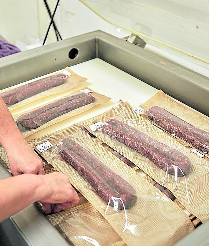 Imagen secundaria 2 - Una trabajadora envasa las piezas de embutido y las etiqueta.