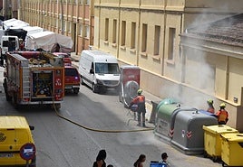 Los bomberos intervienen para apagar el fuego en el contenedor.
