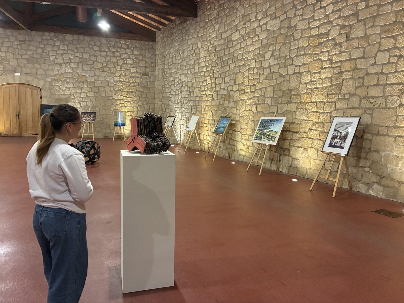 Una chica observa la exposición colectiva Hermanamiento Artistas Jarreros y Jerezanos en Muga.