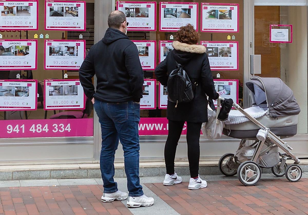 Una pareja mira la oferta de pisos en una inmobiliaria.
