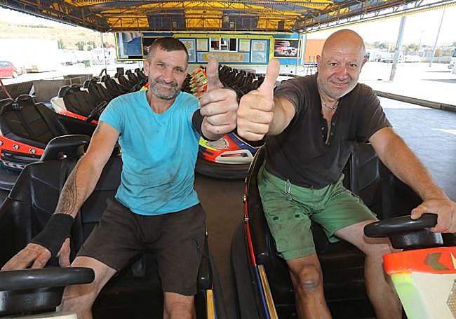 Dos trabajadores ponen a punto los autos de choque.