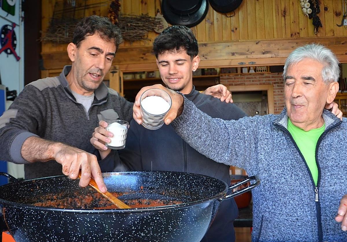 Fernando, Daniel y Vicente, preparando el tomate frito, que condimentan con sal y azúcar.