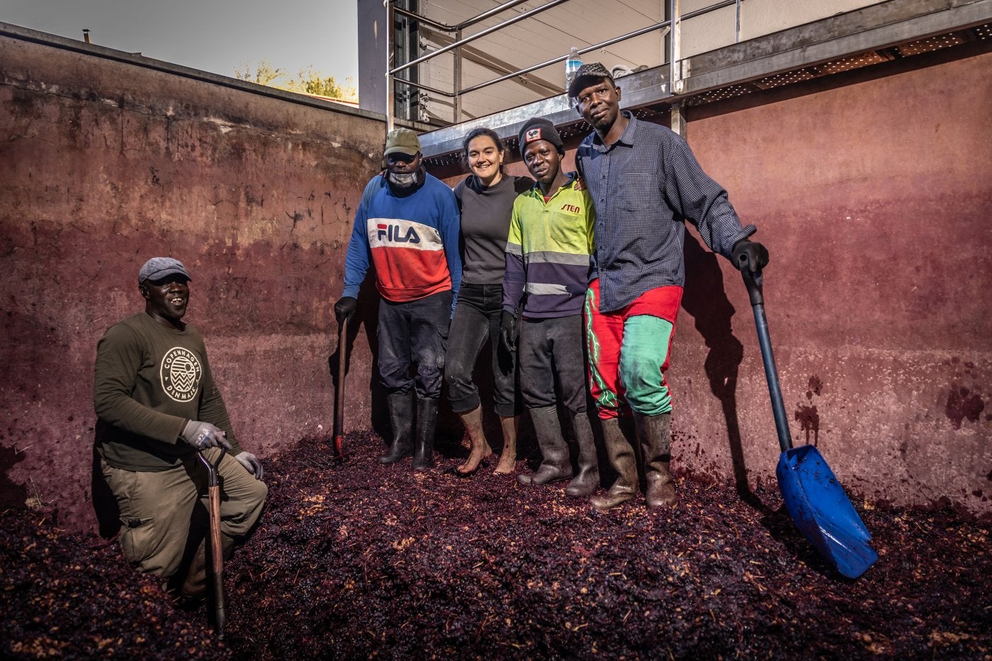 Carmen, con sus trabajadores de temporada, en el lago tradicional de hormigón donde elabora por maceración carbónica.