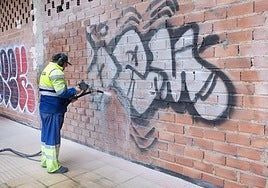 Imagen de un orperario retirando una pintada en una fachada de la ciudad.