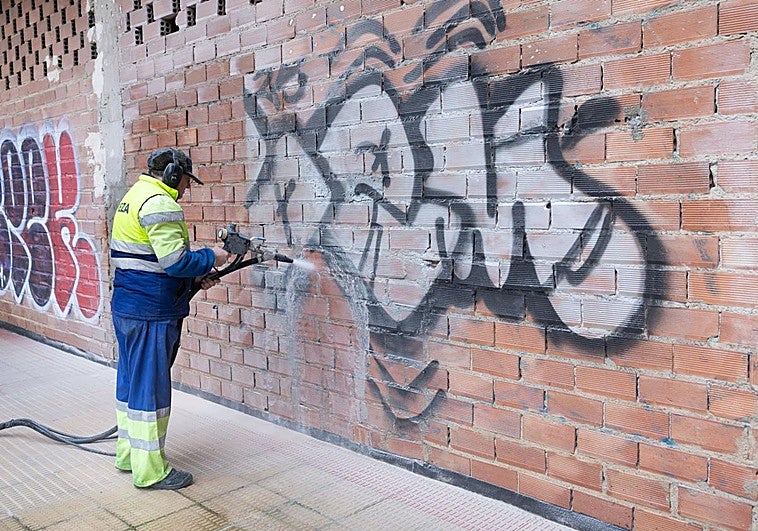 Imagen de un orperario retirando una pintada en una fachada de la ciudad.
