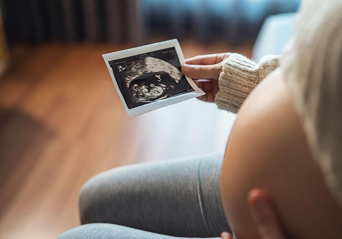 Mujer embarazada mira su informe de ultrasonido.