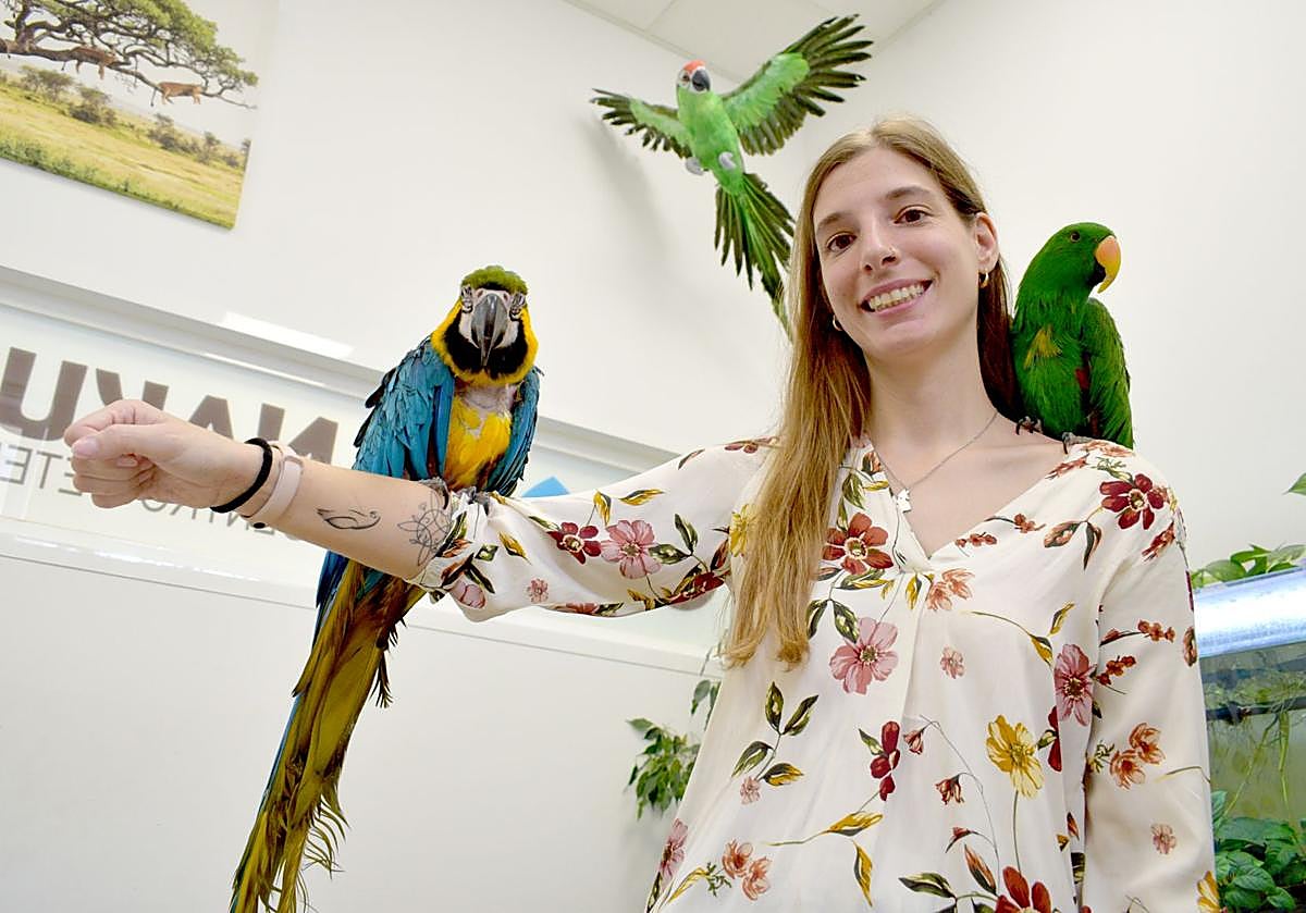 Elena Llop posa con el guacamayo Lora en su mano derecha y el loro Goku en su hombro izquierdo en la clínica veterinaria Nakuru.