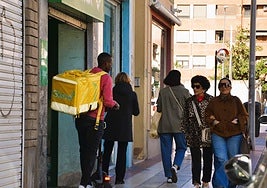 Un repartidor, llevando un monopatín en la mano, después de una entrega en la calle General Gallarza.
