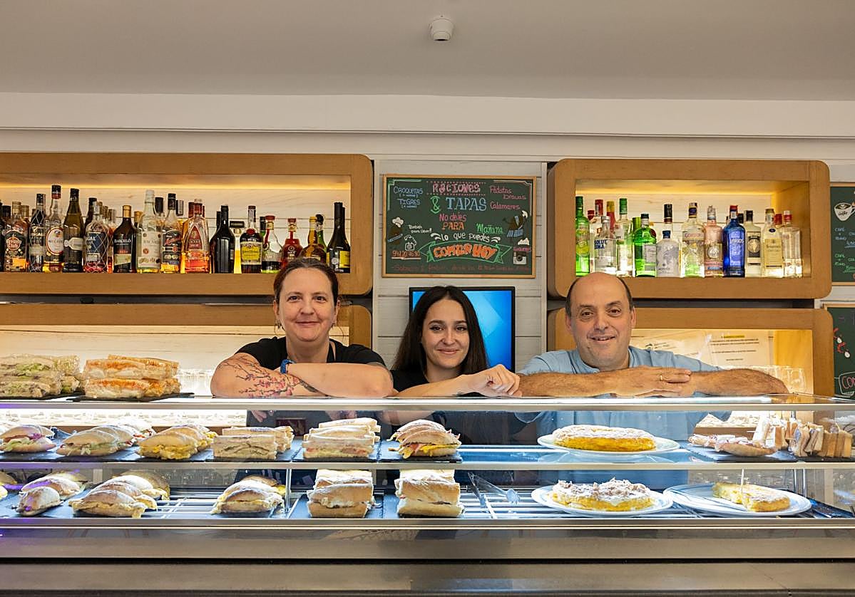 Carlos Belaza posa frente a su nutrida barra matinal, junto a la cocinera y a una de las camareras del Génesis.