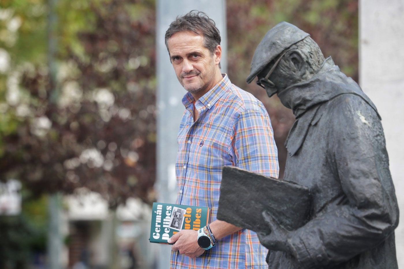 Germán Delibes Caballero posa con su libro junto a la estatua de su abuelo en Valladolid.