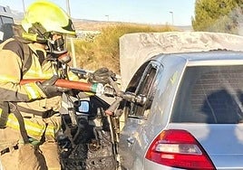 Un bombero sofoca las llamas de uno de los turismos.