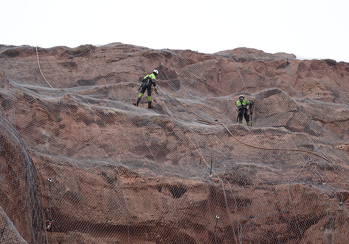 Los operarios trabajando en la malla de la peña, a 80 metros de altura.
