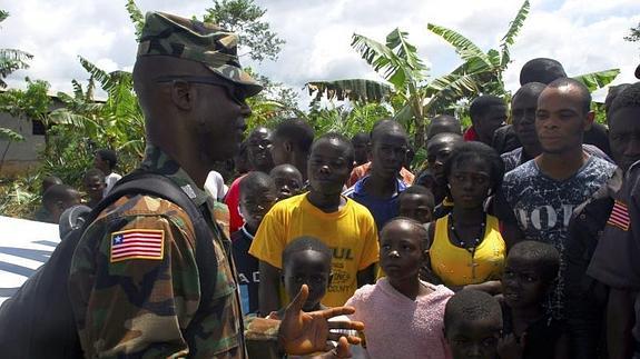 El soldado liberiano Ew Dennis conversa con miembros de una comunidad sobre una unidad de tratamiento del ébola  