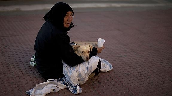 Mujer, junto a su perro, pide limosna en una calle de Málaga 