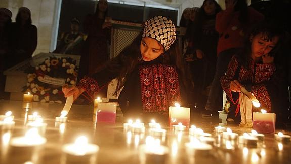 Unas niñas palestinas encienden velas junto a la tumba de Arafat.