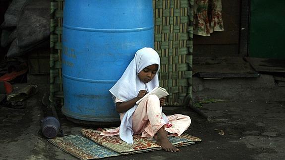 Una niña escribe en un cuaderno en una calle de Bombay.