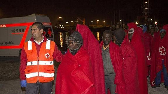 Un miembro de la Cruz Roja acompaña a los 40 subsaharianos que han desembarcado en el puerto de Motril. 