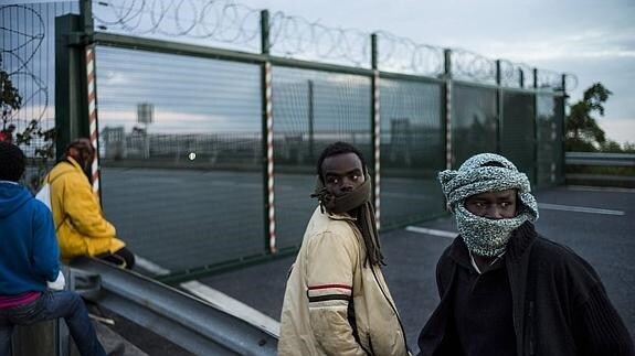 Inmigrantes esperan a intentar cruzar a Inglaterra en el puerto de Calais.