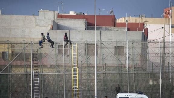 Tres inmigrantes subsaharianos encaramados a la valla de Melilla. 