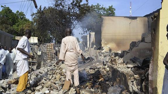 Dos hombres observan escombros tras un atentado en Nigeria.