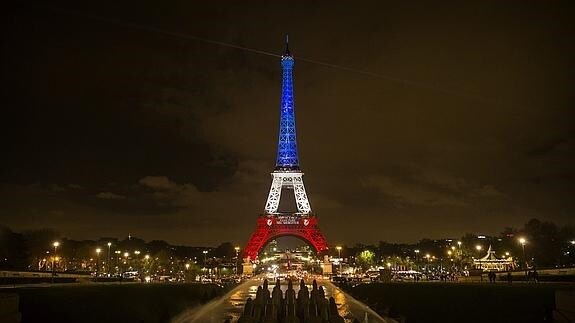 Vista de la torre Eiffel iluminada con los colores de la bandera nacional francesa en París.