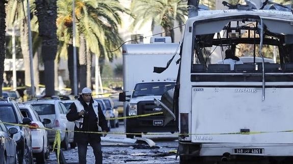 Policías forenses tunecinos inspeccionan los restos del autobús.