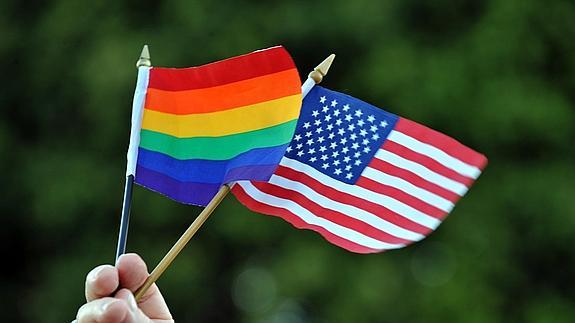 Un hombre sostiene la bandera del orgullo gay junto con la bandera de Estados Unidos.