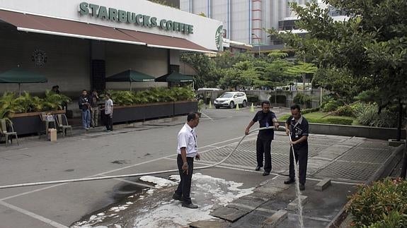 Miembros de las fuerzas de seguridad trabajan en la limpieza del lugar del atentado en Yakarta.