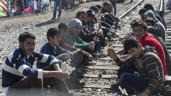 Varios refugiados esperan en la frontera entre Macedonia y Grecia.