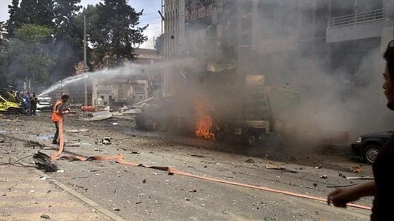 Miembros del cuerpo de bomberos trabajan tras los ataques con cohetes en un distrito residencial de Alepo. 