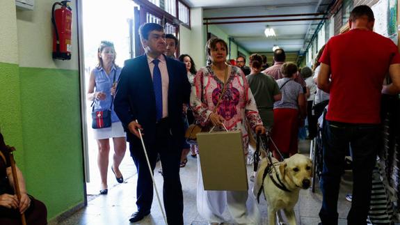 Un matrimonio entra al colegio electoral acompañado de su perro guía. 