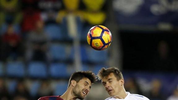 El eibarrés Adrián González (i) salta por el balón con el malaguista Diego Llorente.