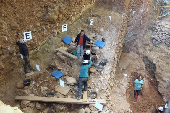 El grupo del Museo de Ciencias de Arnedo, junto a los co-directores Eudald Carbonell y José María Bermúdez. A la derecha, el yacimiento de la Sima del Elefante. 