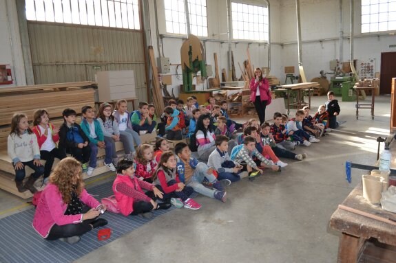 El grupo de pequeños de seis años, con sus profesoras, atienden al carpintero. 