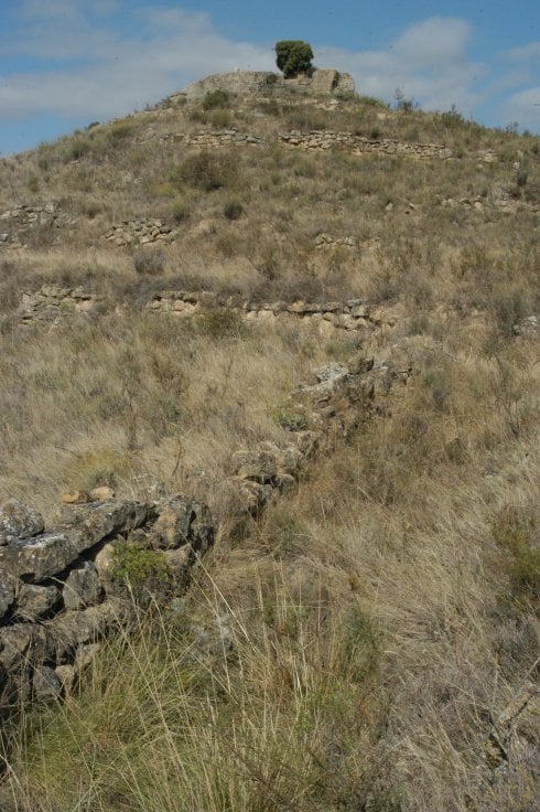 Camino amurallado en forma de zigzag que conduce desde un lagar rupestre hasta lo alto de Peña Redonda, donde parece haber un antiguo santuario. En detalle, una inscripción en la piedra. 