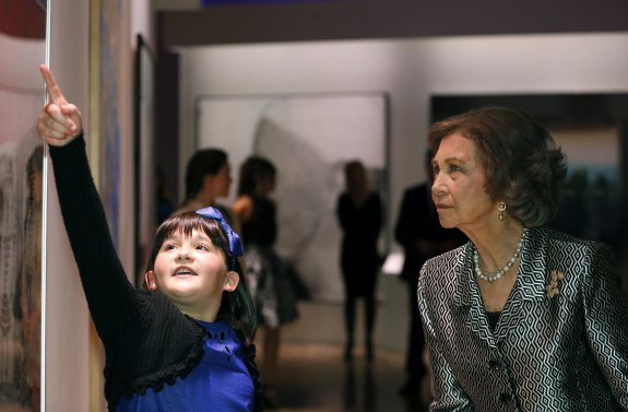 La joven Paloma Ruiz Moreno le muestra a la reina Sofía el cuadro con el que ha ganado el Premio BMW de Pintura. 