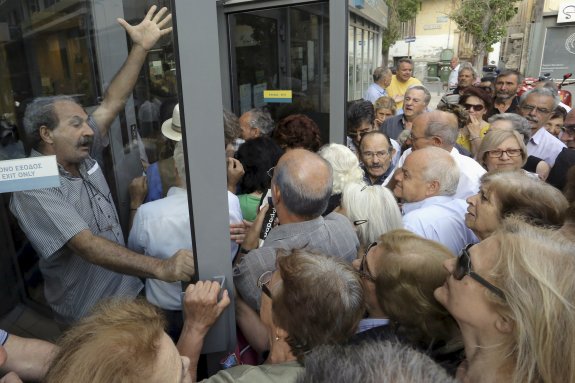 Un grupo de jubilados intenta entrar en un banco para sacar su pensión. :: Stefanos Rapanis / reuters