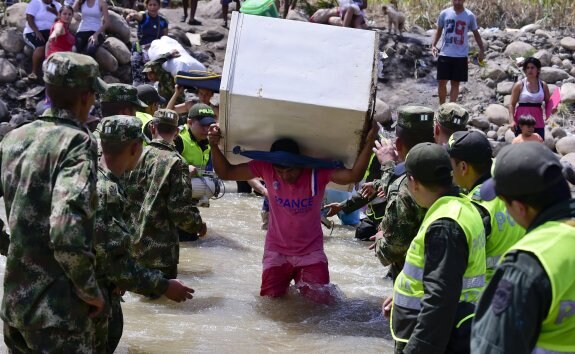 Ciudadanos colombianos dejan Venezuela con sus pertenencias a cuesta a través de la frontera con el río Táchira. :: LUIS ACOSTA / afp