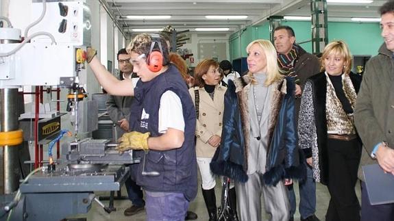 Un joven trabaja con un taladro en un taller de mecanizados. 