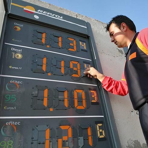 Un operario cambia los precios de los carburantes. 