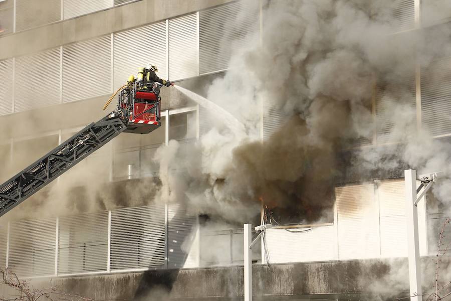 Unos bomberos tratan de sofocar un incendio desde el exterior de una vivienda. 