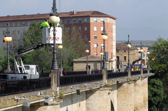 Los operarios municipales utilizaron las grúas para supervisar una a una las 18 farolas que adornan el Puente de Piedra. :: JUSTO RODRÍGUEZ