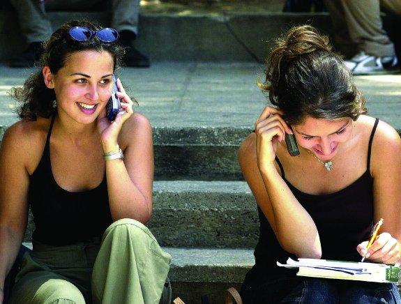 Dos jóvenes conversan por teléfono móvil durante las vacaciones. 