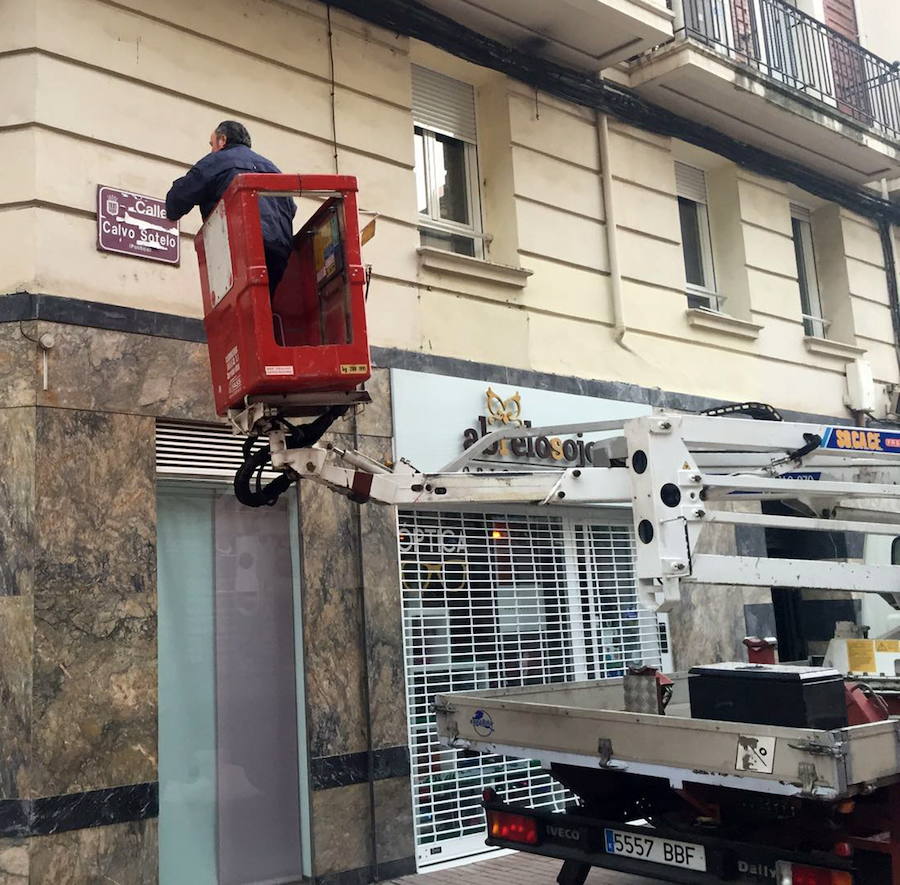 Un operario municipal retira las pegatinas colocadas por el colectivo 'La Barranca' sobre el cartel de la calle Calvo Sotelo. 
