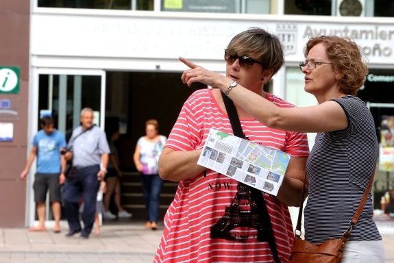 Dos turistas señalan la dirección que van a tomar después de consultar el mapa de la ciudad. 