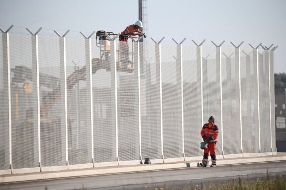 Dos operarios trabajan en la valla con la que se tratará de impedir el acceso de los inmigrantes al puerto de Calais. :: C. Platiau / REUTERS