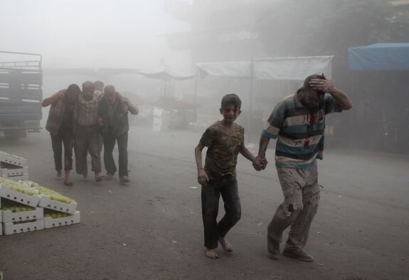 Varios hombres y un niño heridos se abren paso entre el humo tras una ofensiva aérea contra Idlib. 