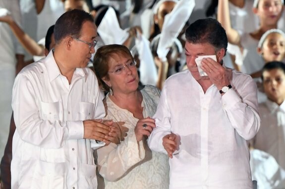 El secretario general de la ONU, Ban Ki-moon, y la presidenta de Chile, Michelle Bachelet, arropan a un emocionado Juan Manuel Santos.

