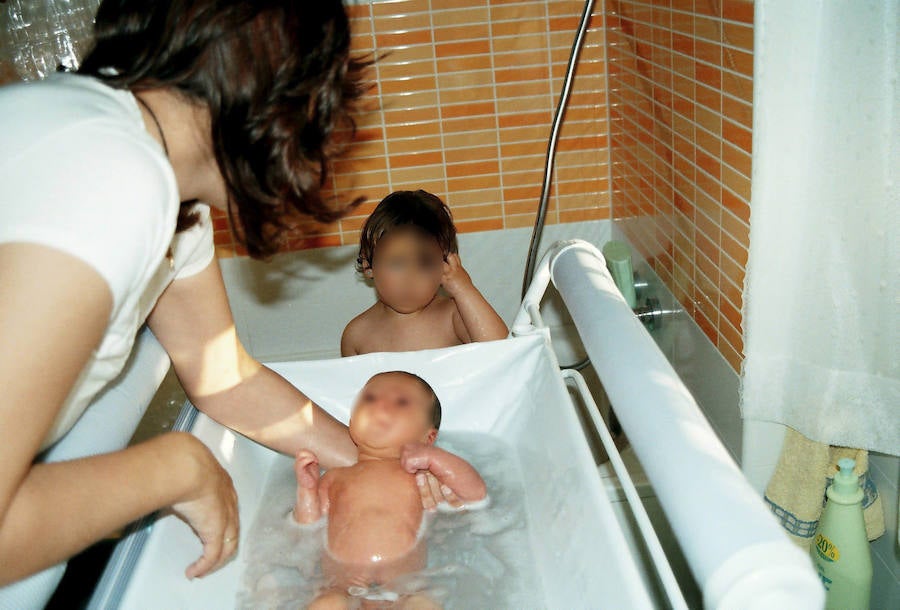 Una madre baña a sus dos hijos. 