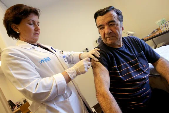 La enfermera Eden Lizaranzu pone la vacuna contra la gripe a Rufino Echazarreta. 